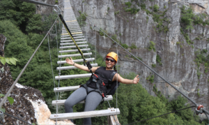 Young adult female walking on adventure challenge bridge over a canyon